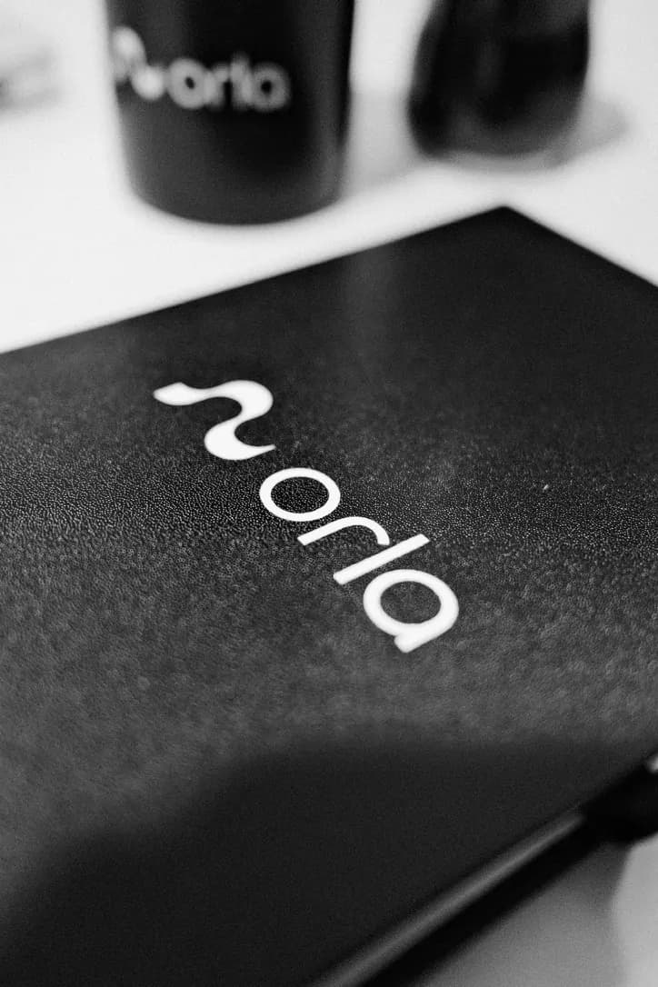 Caderno preto com a marca da Orla sobre a mesa