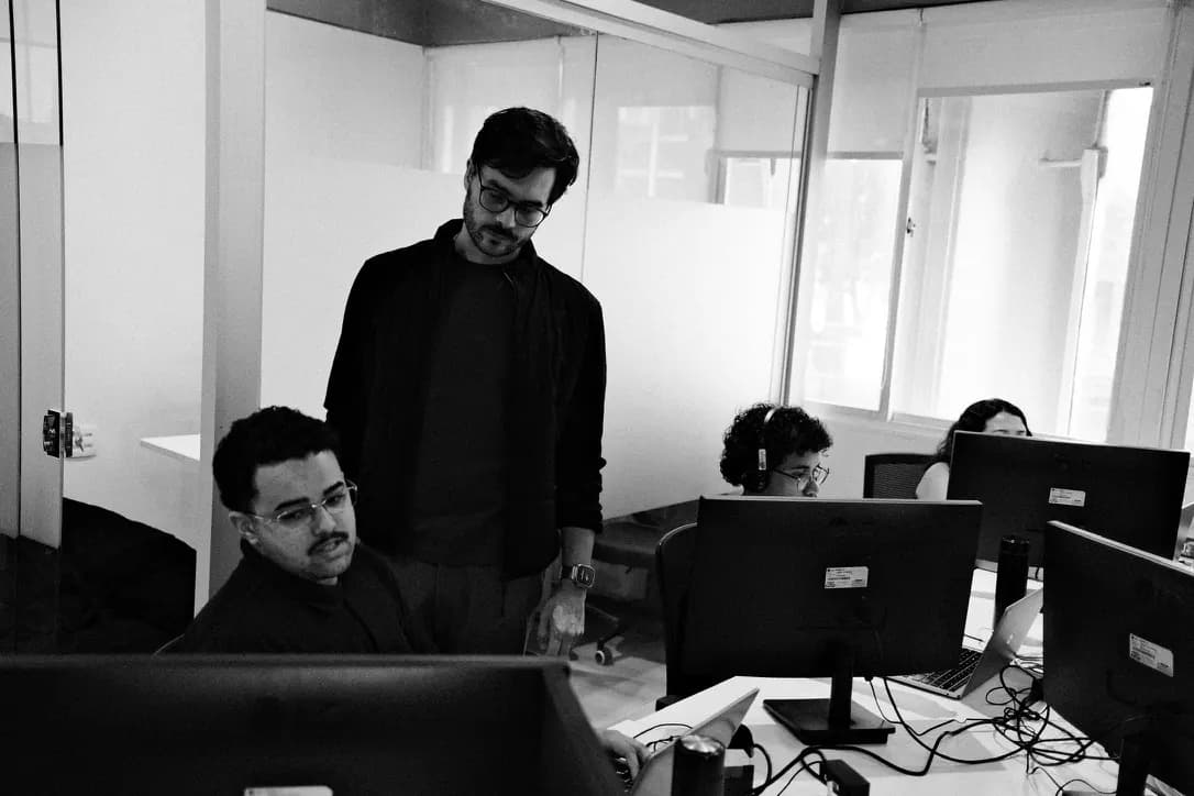 Uma pessoa acompanha de pé o trabalho de um colega no computador